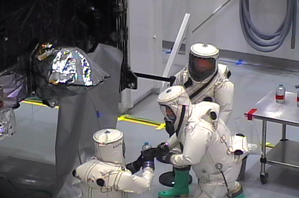 Propellant technicians in SCAPE performing point of use sample by spacecraft